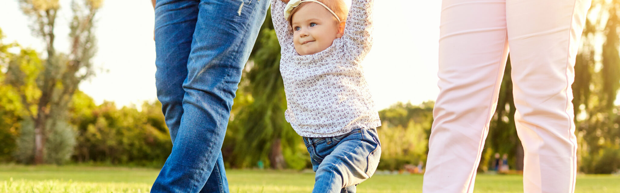 Les premiers pas du bébé. Les parents apprennent à leur enfant à marcher. Une famille heureuse.